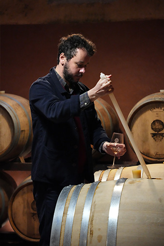 Lorenzo in the cantina pulling wine to taste from an oak barrel.